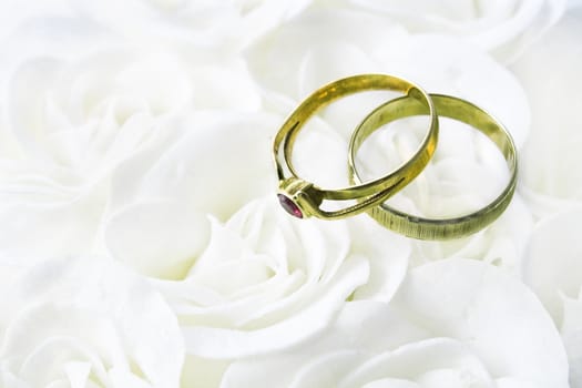 Two wedding rings over white roses 