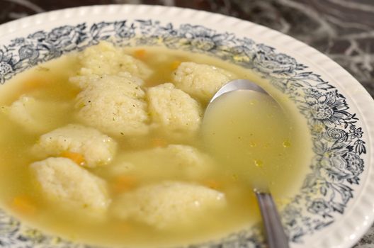 traditional chicken matzo ball soup served in a decorated plate