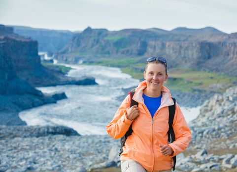 Cute woman hiking in the canyon Dettifoss waterfall in Vatnajokull National Park, Northeast Iceland.