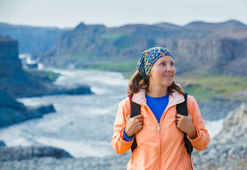 Cute woman hiking in the canyon Dettifoss waterfall in Vatnajokull National Park, Northeast Iceland.