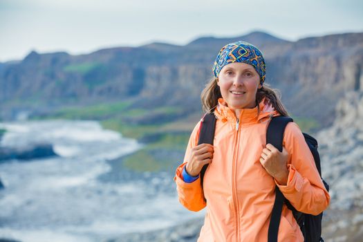 Cute woman hiking in the canyon Dettifoss waterfall in Vatnajokull National Park, Northeast Iceland.