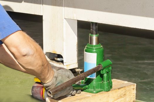 man lifting using hydraulic floor jack for car and truck, closeup