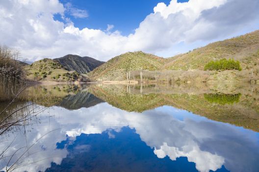 Sky, clouds and hils reflection on lake