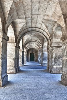 Strong marble arches with a green door at the end of the tunel, image with a lot of texture.