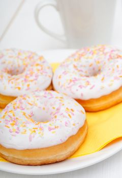 Donuts With Colorful Sprinkles, Plates and Mugs on Table - Shallow Depth Of Field
