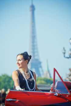 Young happy woman in retro-style travel in a car in Paris. Vertical view