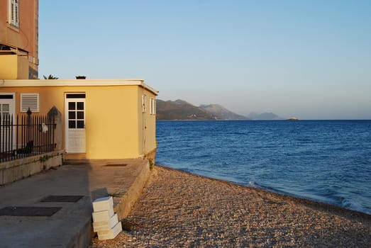 Yellow house,gravel shore,sea,sky