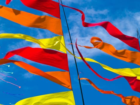 Red, Orange, and Yellow Flags Waving in a Blue Sky