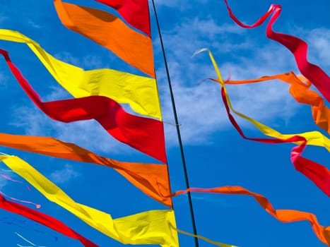 Red, Orange, and Yellow Flags Waving in a Blue Sky