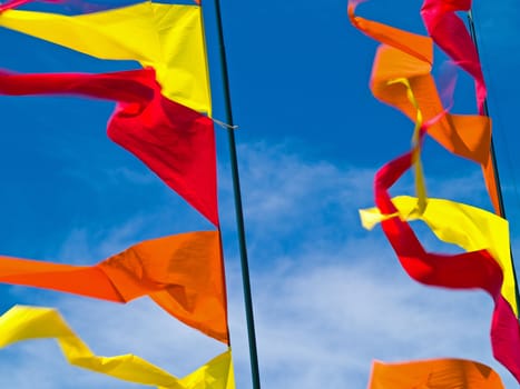 Red, Orange, and Yellow Flags Waving in a Blue Sky