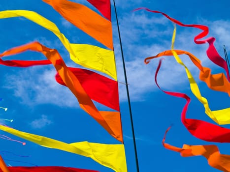 Red, Orange, and Yellow Flags Waving in a Blue Sky