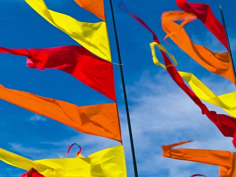 Red, Orange, and Yellow Flags Waving in a Blue Sky