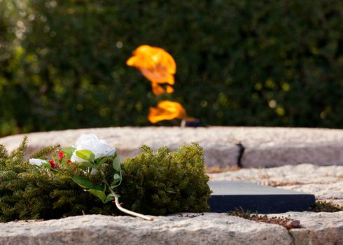 Xmas wreath and white rose lay by the side of the everlasting flame at President Kennedy memorial in Arlington Cemetery