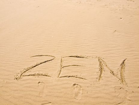 Zen Written in the Sand on a Sunny Day with Footprints