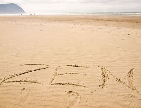 Zen Written in the Sand on a Sunny Day with Footprints