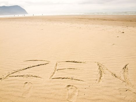 Zen Written in the Sand on a Sunny Day with Footprints