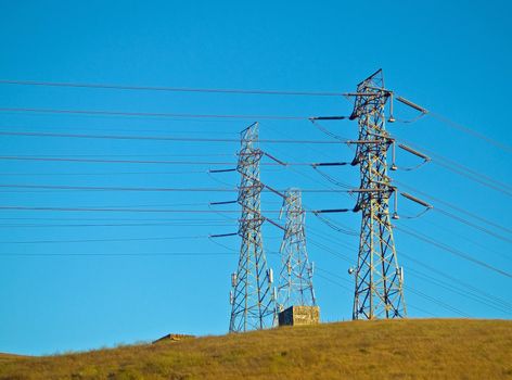 Electrical Powerlines on a Hill before a Blue Sky