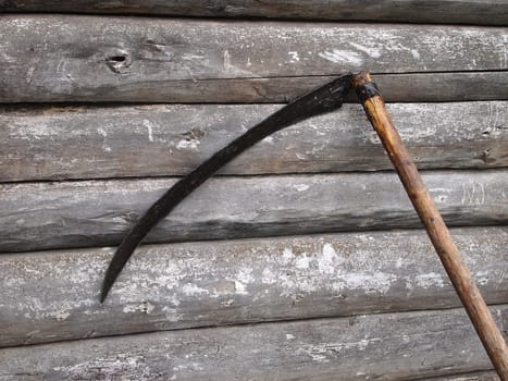scythe at the old log walls
