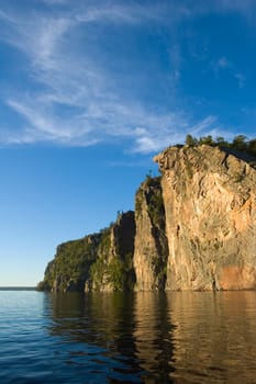 High cliff at shore of Mazinaw Lake in sunset light
