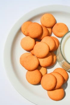 Close up of vanilla cookies and a glass of milk.
