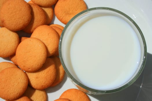 Close up of vanilla cookies and a glass of milk.
