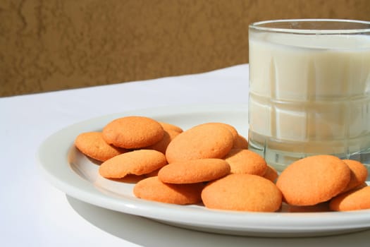 Close up of vanilla cookies and a glass of milk.
