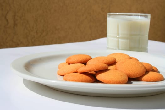 Close up of vanilla cookies and a glass of milk.
