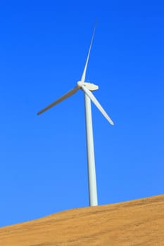 Close up of a wind turbine over blue sky.
