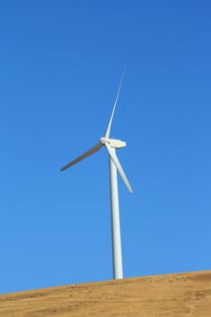 Close up of a wind turbine over blue sky.
