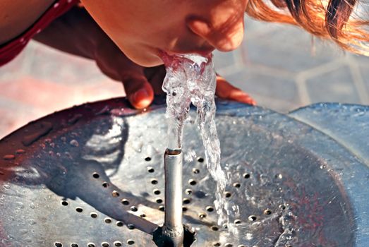 Girl drinking on water fountain outdoor close up