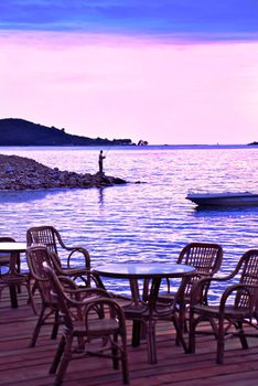 pink sunset from wooden terrace, man fishing