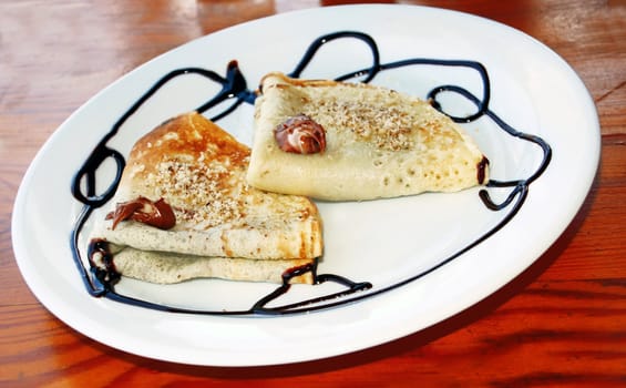 appetizing pancakes with chocolate on white plate