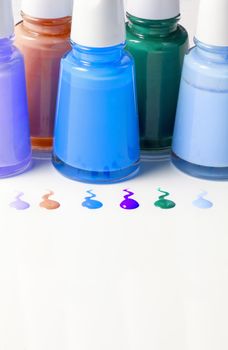 Bottles with spilled nail polish over white background