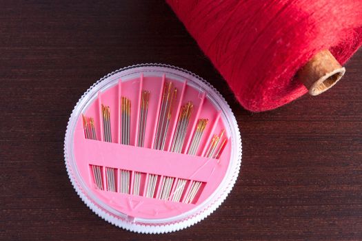 pack of needles and a skein of thread on a wooden background