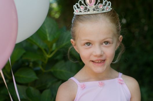 Little girl dressing up as a fairy-tale ballet princess on her birthday in forest garden