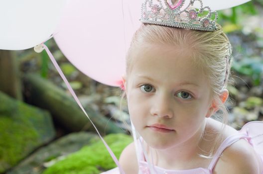 Little girl dressing up as a fairy-tale ballet princess on her birthday in forest garden