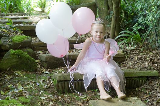 Little girl dressing up as a fairy-tale ballet princess on her birthday in forest garden