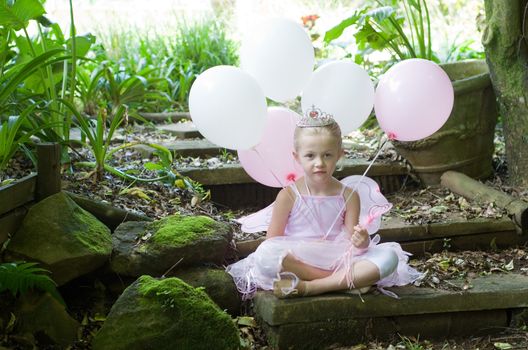 Little girl dressing up as a fairy-tale ballet princess on her birthday in forest garden