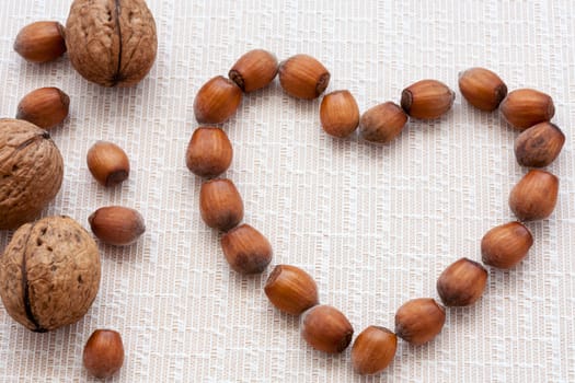 walnuts, hazelnuts on a wooden background in the form of heart