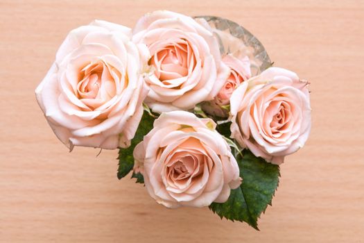 pink roses in a vase on a wooden desk