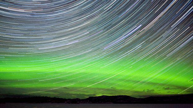 Astrophotography star trails with green glowing display of Northern Lights or Aurora borealis in Yukon Territory  Canada