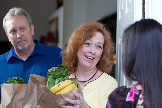 Woman delivers bags of food to the home of a down on their luck couple who have been laid off from their jobs.