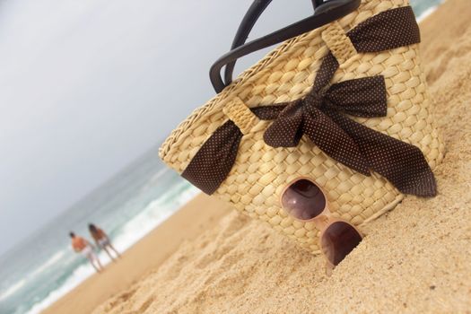 Beautiful straw bag on the beach and pair in love
