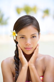 Spa woman wellness beauty woman portrait. Natural outdoors portrait of multicultural woman showing natural beauty looking at camera with flower in the hair. Mixed race Asian Caucasian girl in tropics.