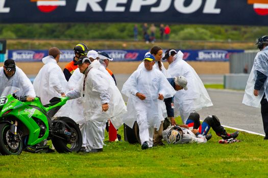 JEREZ DE LA FRONTERA, SPAIN - NOV 20: Race stewards removin the motorcycle 53 while Miguel Lopez is lying-down in the CEV Championship race on November 20, 2011 in Jerez de la Frontera, Spain