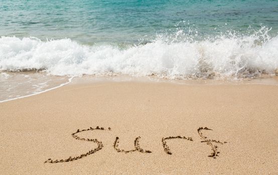 Sand drawing on warm beach by ocean surf in Caribbean spelling surf