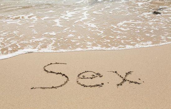 Sand drawing on warm beach by ocean surf in Caribbean spelling Sex