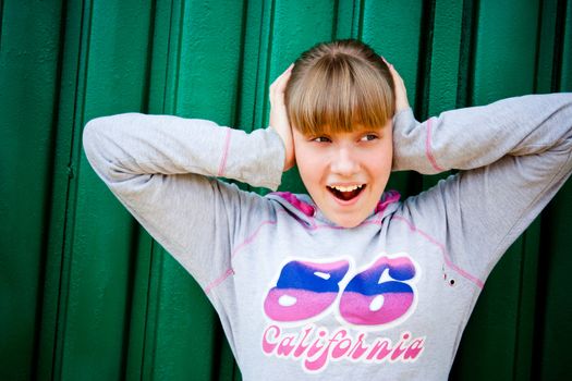 teenage girl hiding from noise on a green background