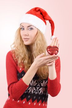 Woman in Santa hat holding red heart over light red back