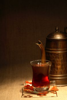 Still life with oriental tea cup near copper teapot on canvas surface